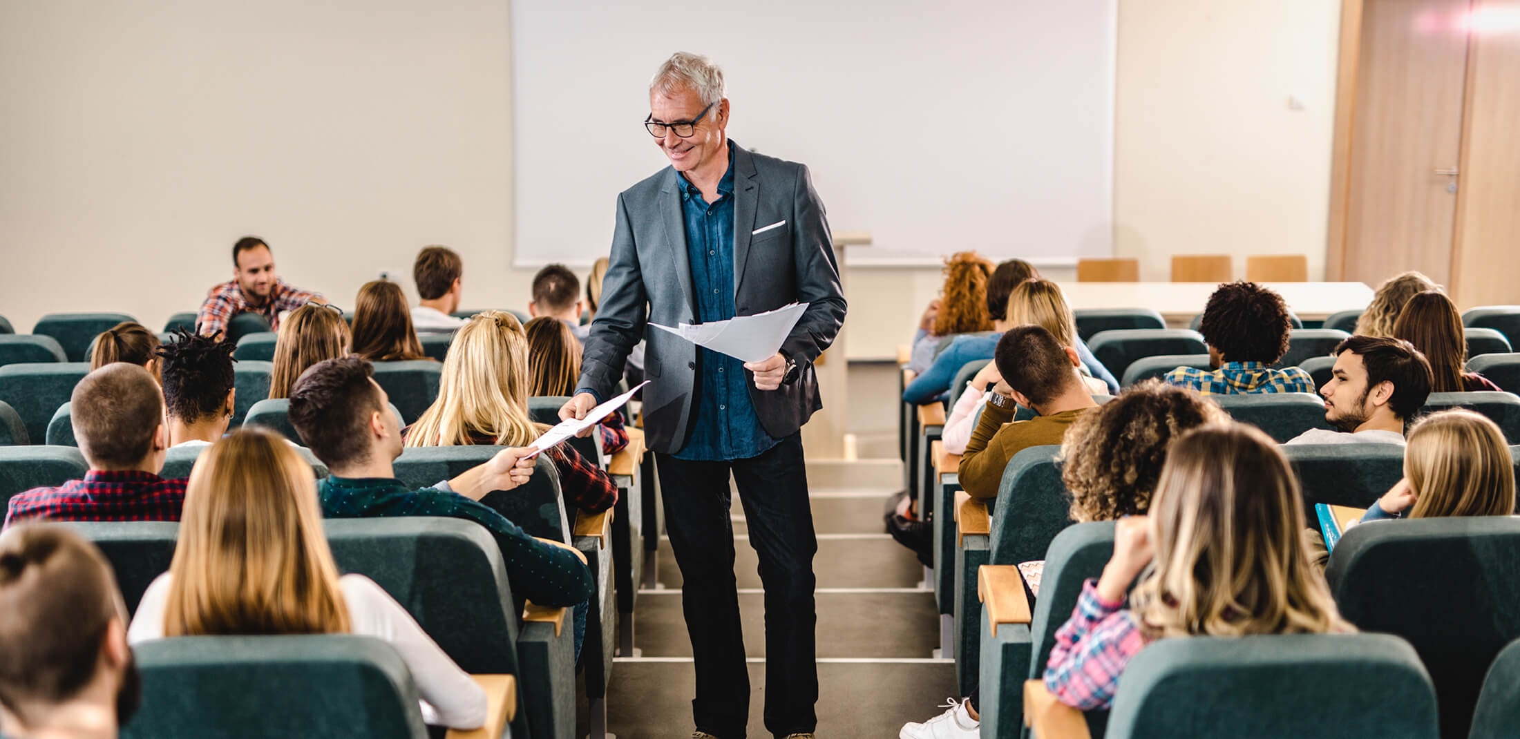 Professor handing out papers to students in class