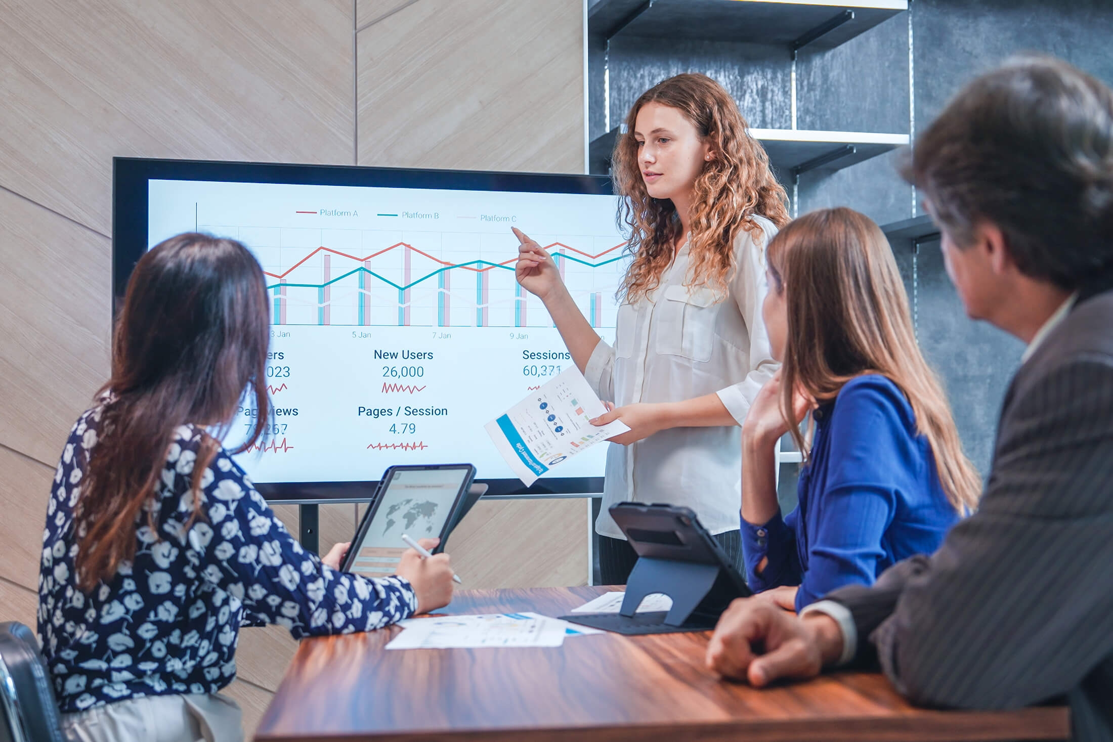 A women doing a presentation and pointing to a data graph on the digital screen