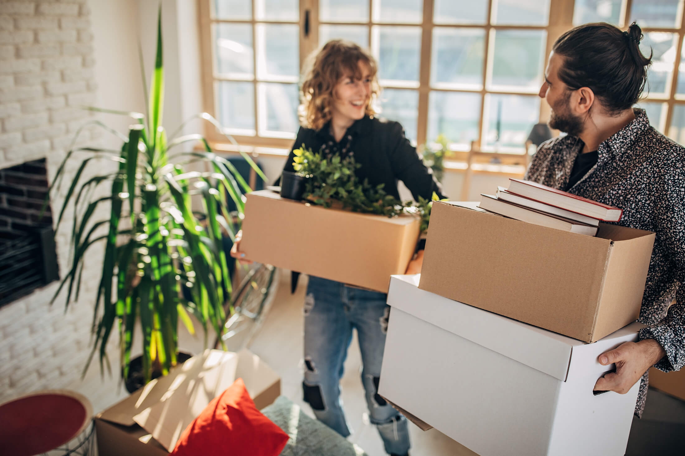 two people carrying boxes and moving in a house