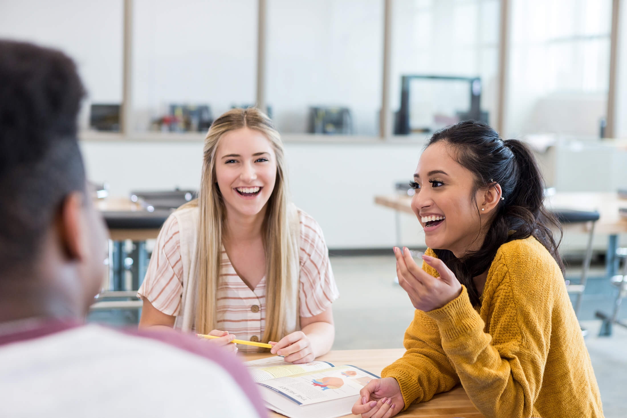 Cheerful diverse students smile and laugh together while studying for biology exam.