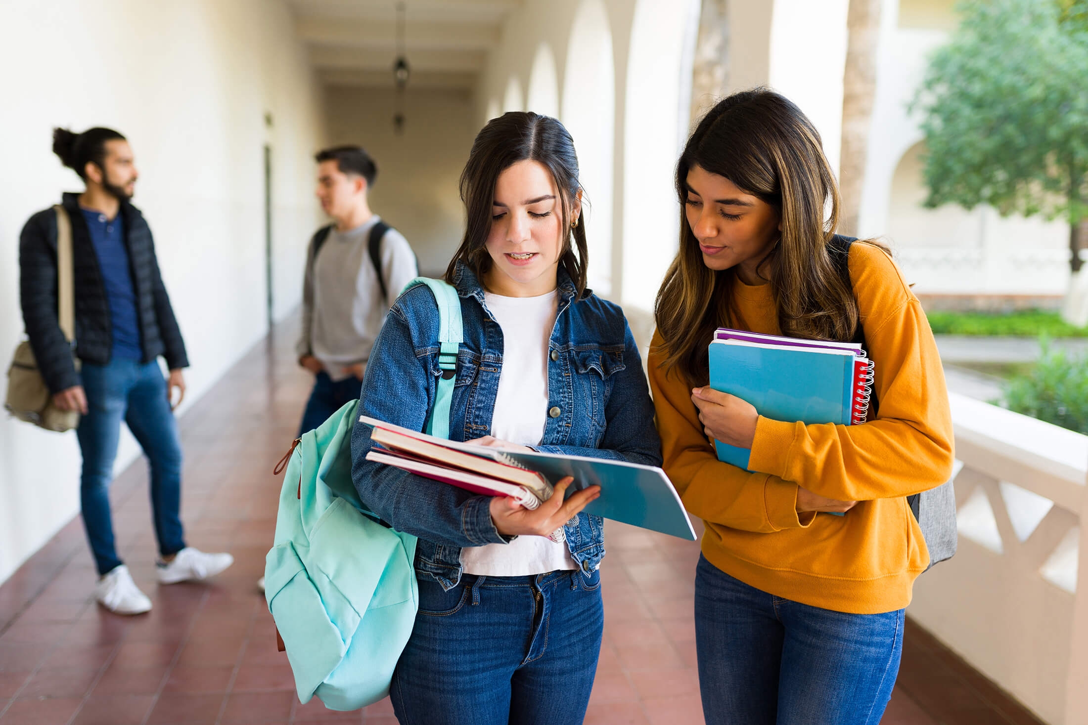 Hispanic and caucasian students checking the homework before coming in to their class