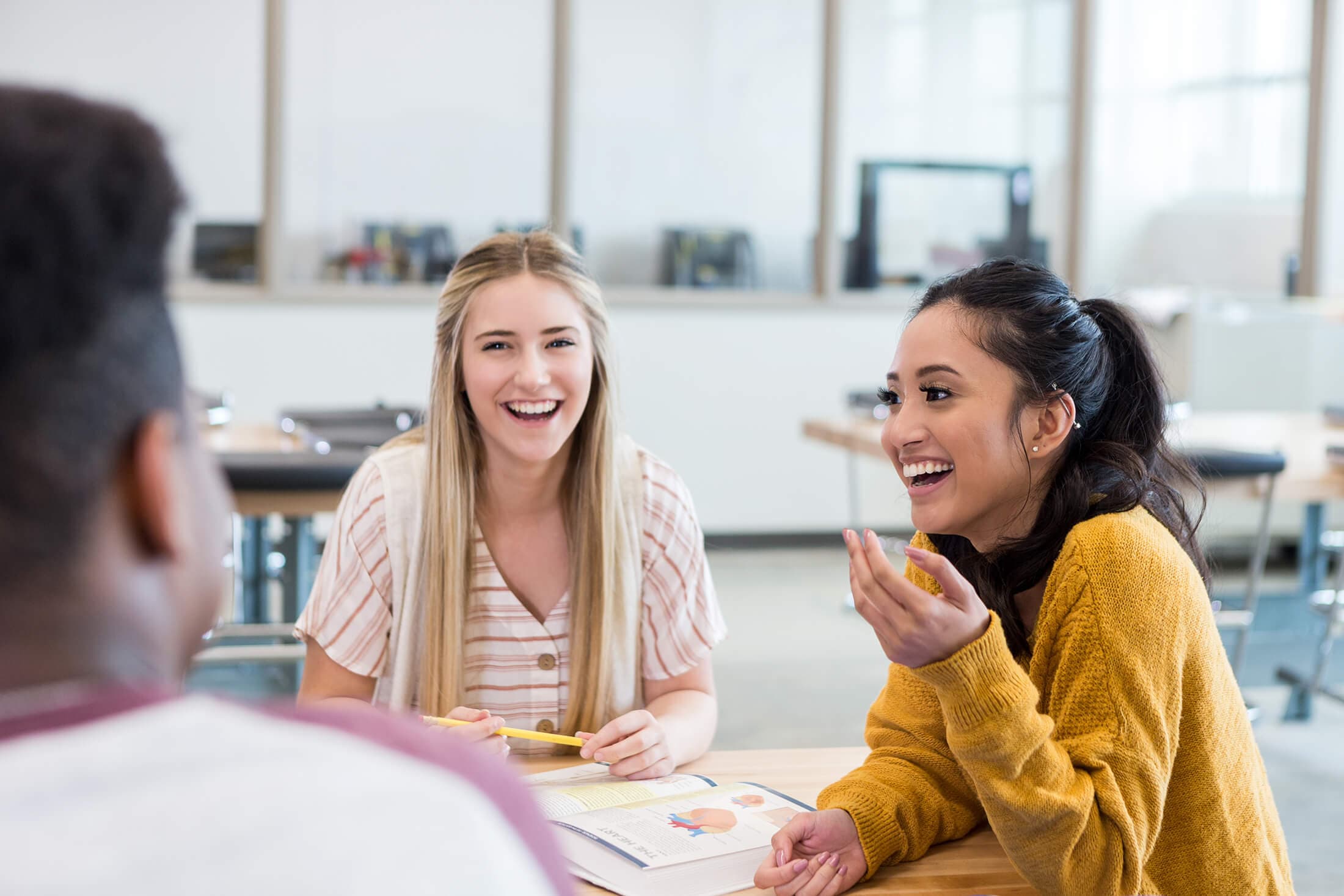 Cheerful diverse students smile and laugh together while studying for biology exam.