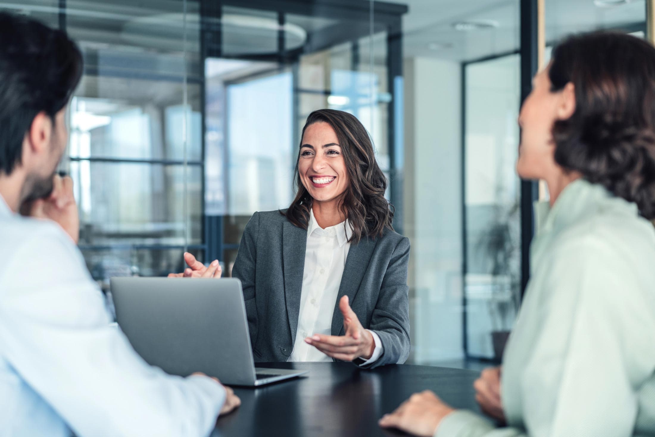 Smiling woman in business meeting talking with two professionals.