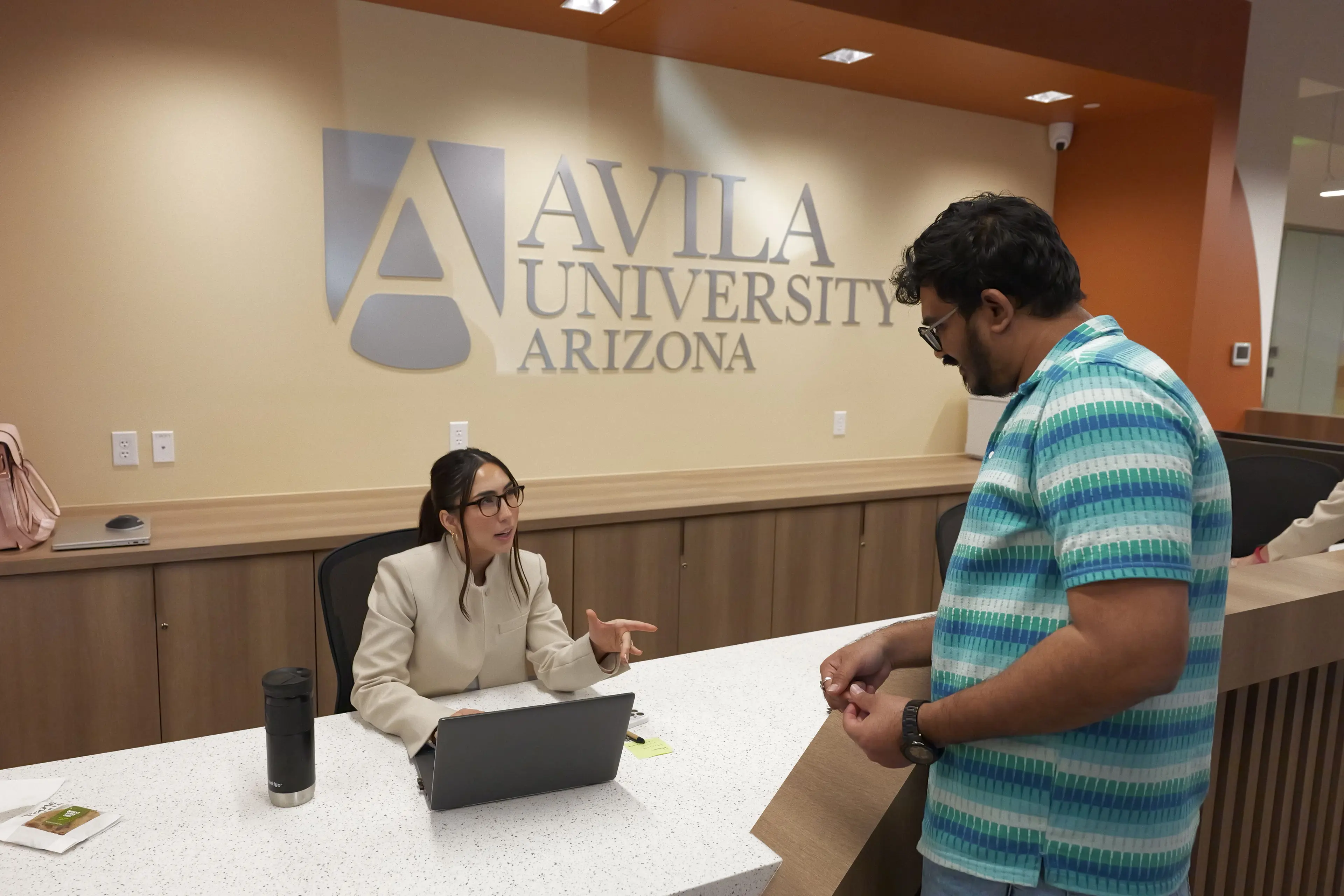 University staff assisting a visitor at the front desk.