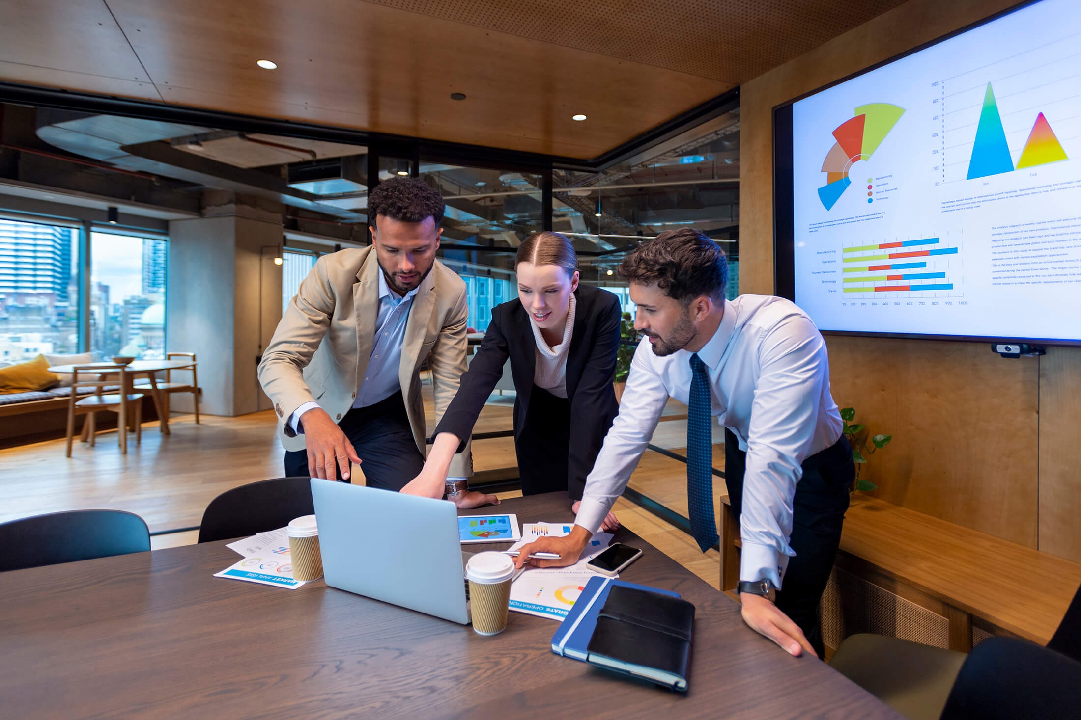 Three business people working at a office setting and looking at laptop
