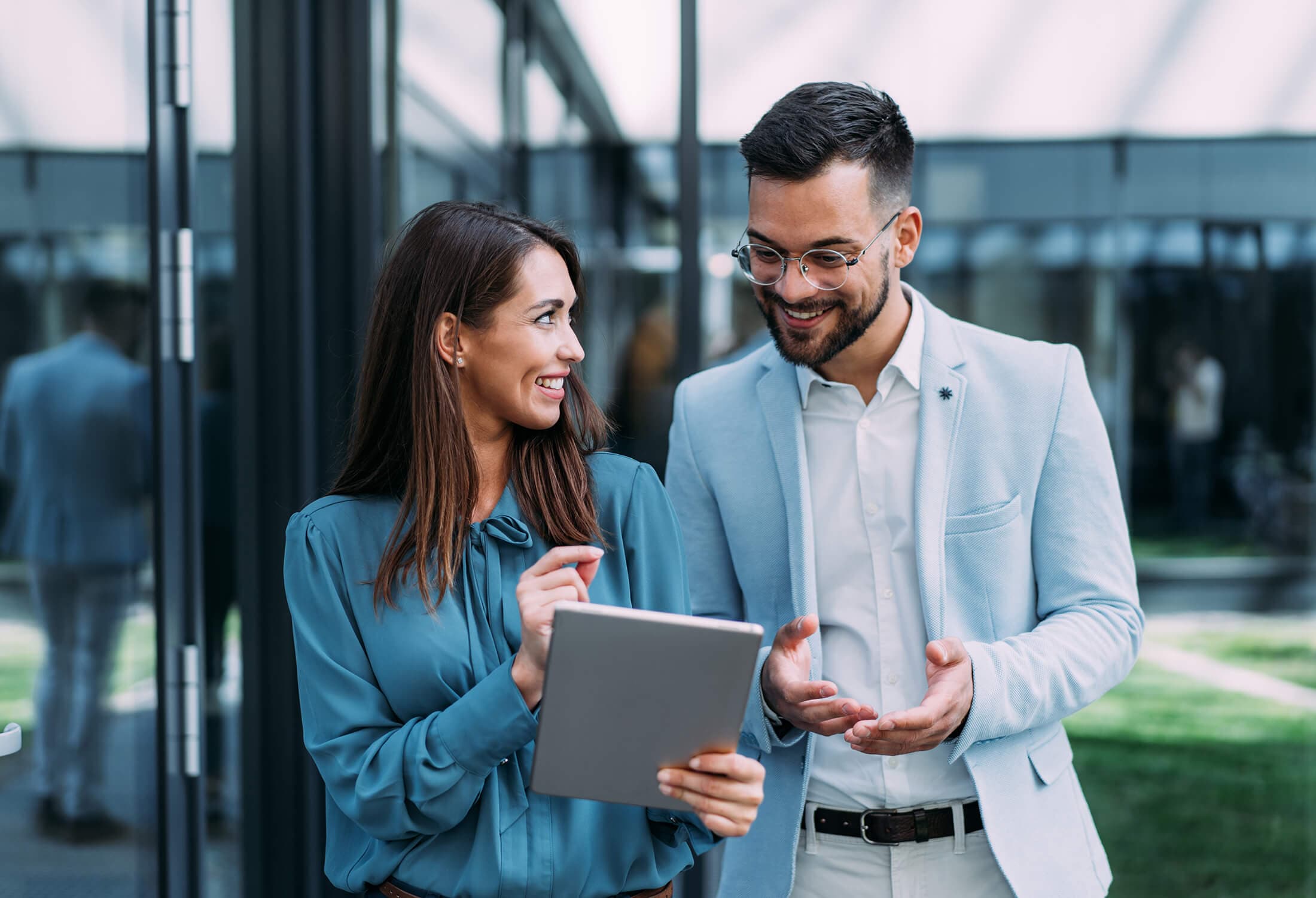 Two people using a tablet and talking smiling